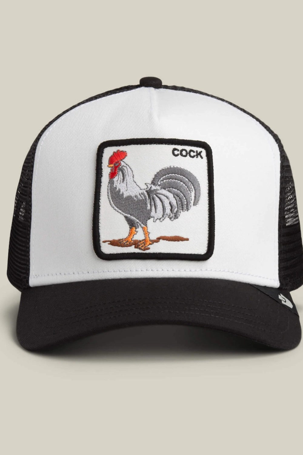 A black and white trucker hat featuring a square embroidered patch on the front with a rooster illustration and the word 'COCK'.