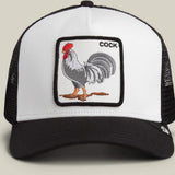 A black and white trucker hat featuring a square embroidered patch on the front with a rooster illustration and the word 'COCK'.