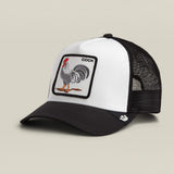 A black and white trucker hat featuring a square patch on the front with a rooster illustration and the word 'COCK'. The hat has a white front panel, black brim, and black mesh back.