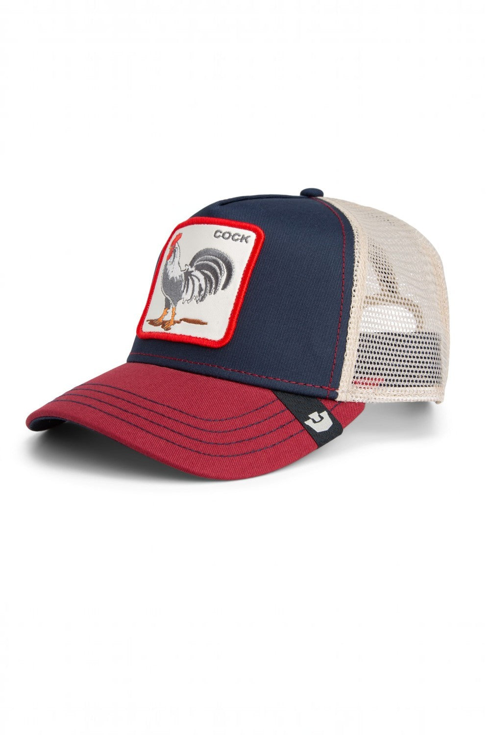 A trucker-style baseball cap with a navy blue front panel, a red brim, and beige mesh back panels. It features a square embroidered patch on the front with a rooster illustration and the word 'COCK'.