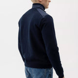 Man wearing a navy blue sweater and jeans on a white background