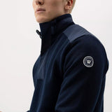Man wearing a navy blue sweater with a logo on a white background