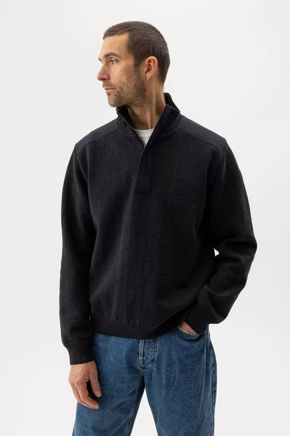 Man wearing a black jacket and blue jeans on a white background