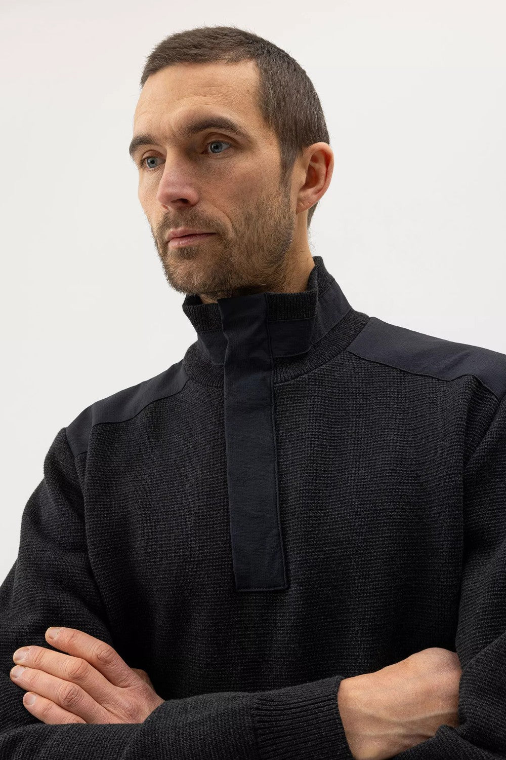 Man wearing a black high-neck sweater against a plain background