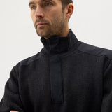 Man wearing a black high-neck sweater against a plain background
