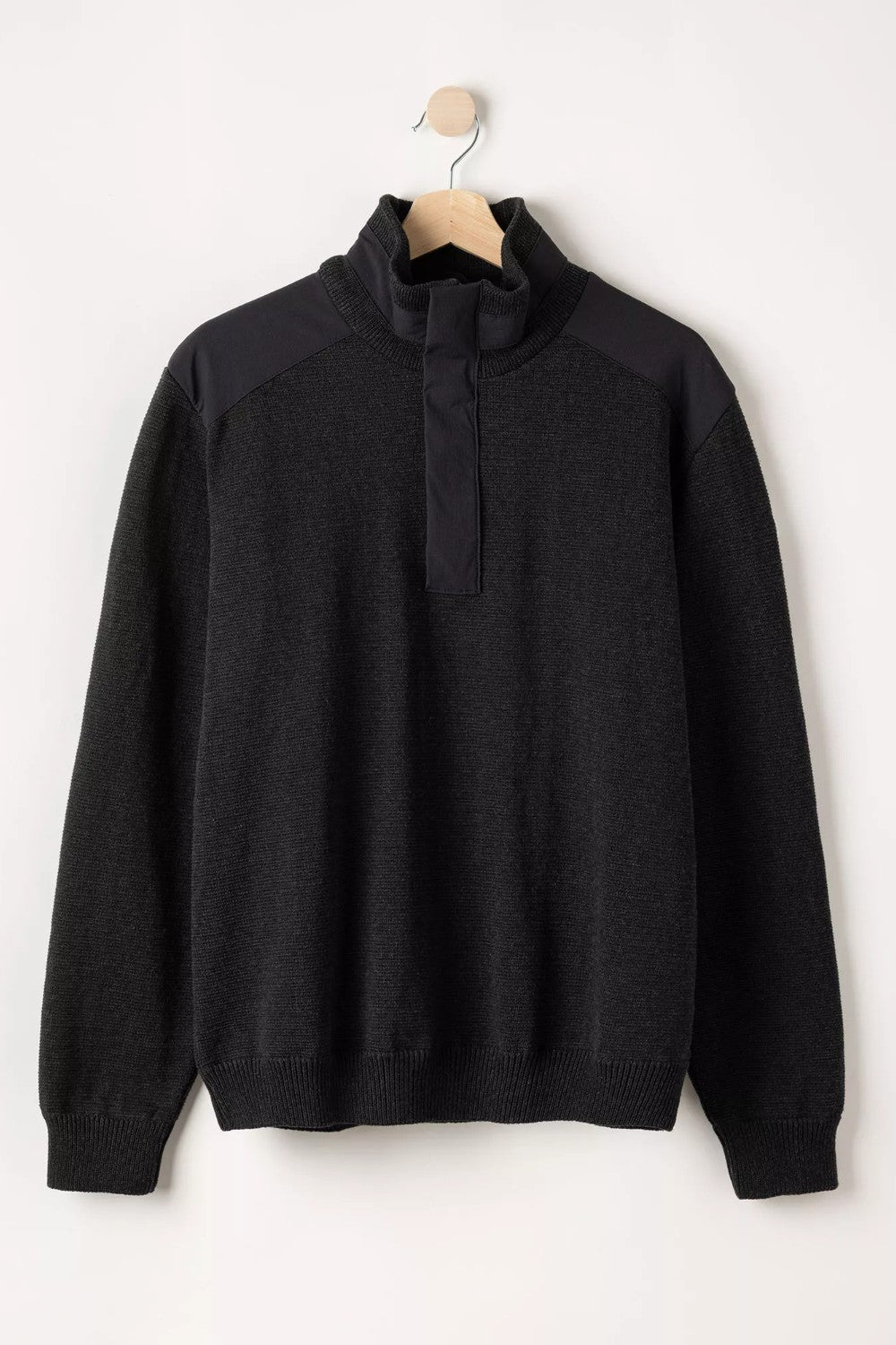 Black sweater on a hanger against a white background