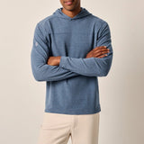 Man wearing a blue hoodie and beige pants against a plain background
