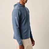 Man wearing a blue hoodie and beige pants on a plain background