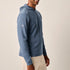 Man wearing a blue hoodie and beige pants on a plain background