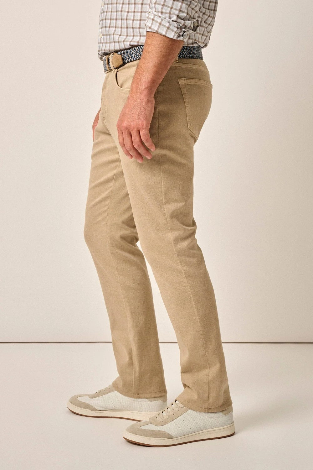 Person wearing beige pants and white sneakers on a plain background