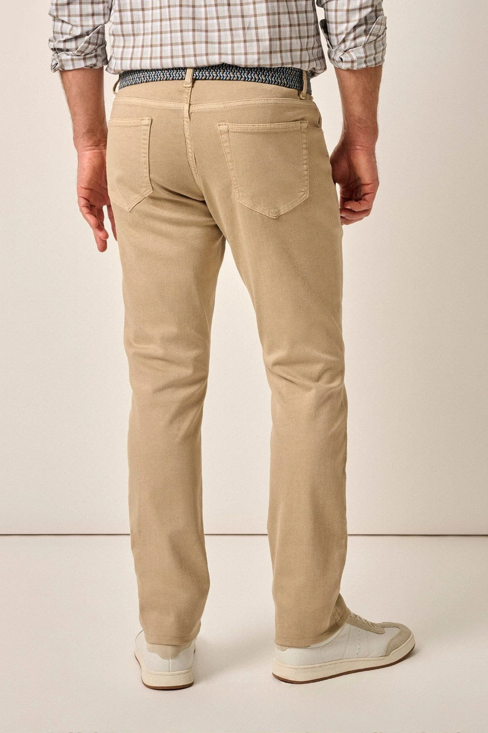 Person wearing beige pants and a plaid shirt on a plain background