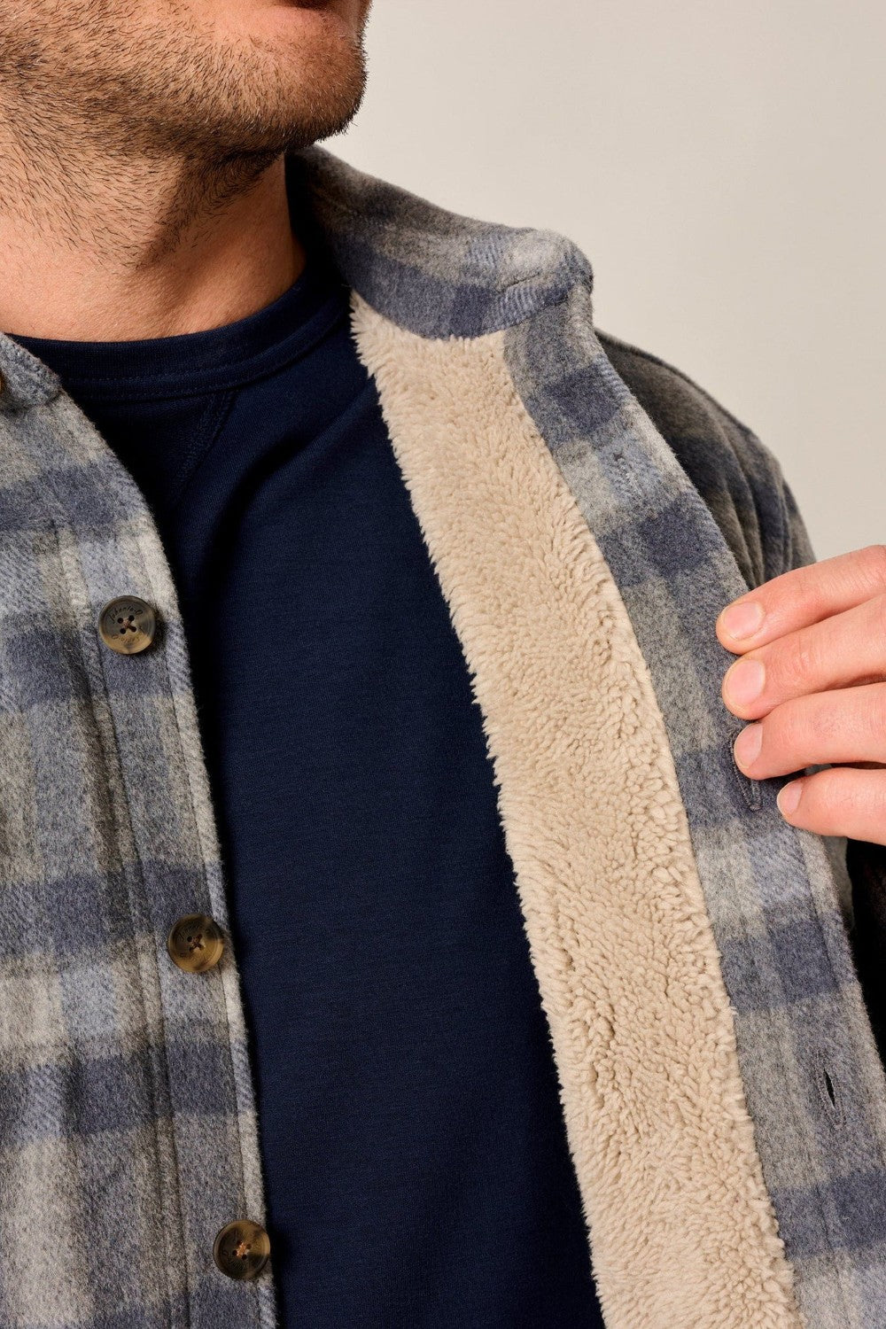 Person wearing a plaid shirt with a fleece lining, focusing on the collar area.