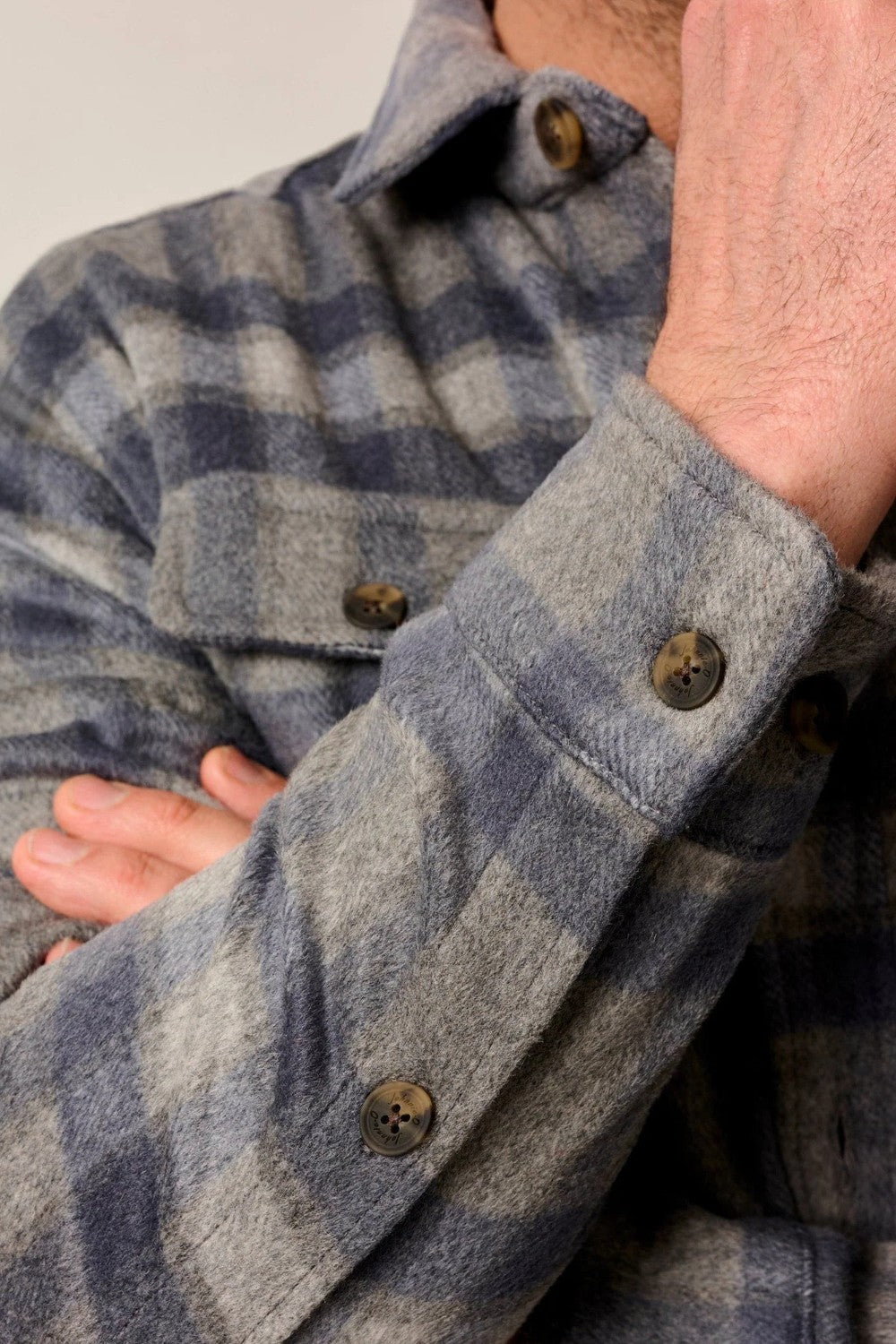 Close-up of a person wearing a blue and gray plaid shirt with buttons.