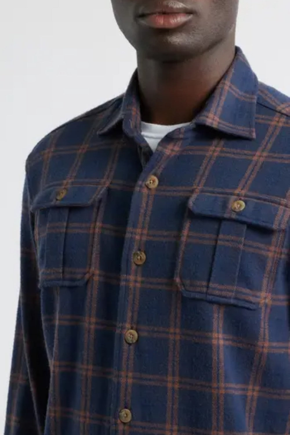 Man wearing a blue plaid shirt with a plain background