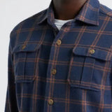 Man wearing a blue plaid shirt with a plain background
