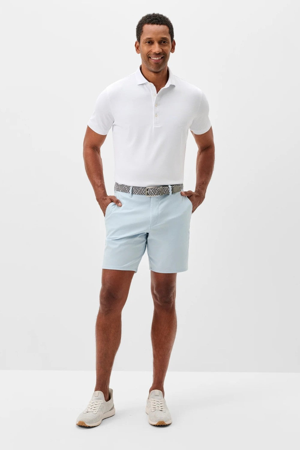 Man wearing a white polo shirt and light blue shorts on a white background