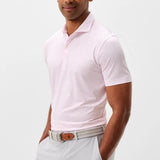 Man wearing a pink patterned polo shirt and light gray pants on a white background