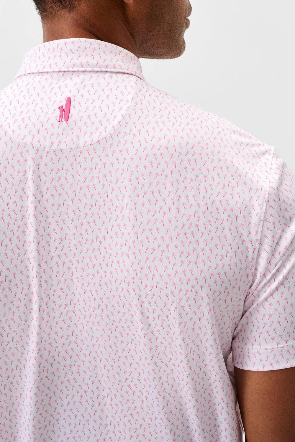 Person wearing a light pink patterned polo shirt with a small logo on the chest.