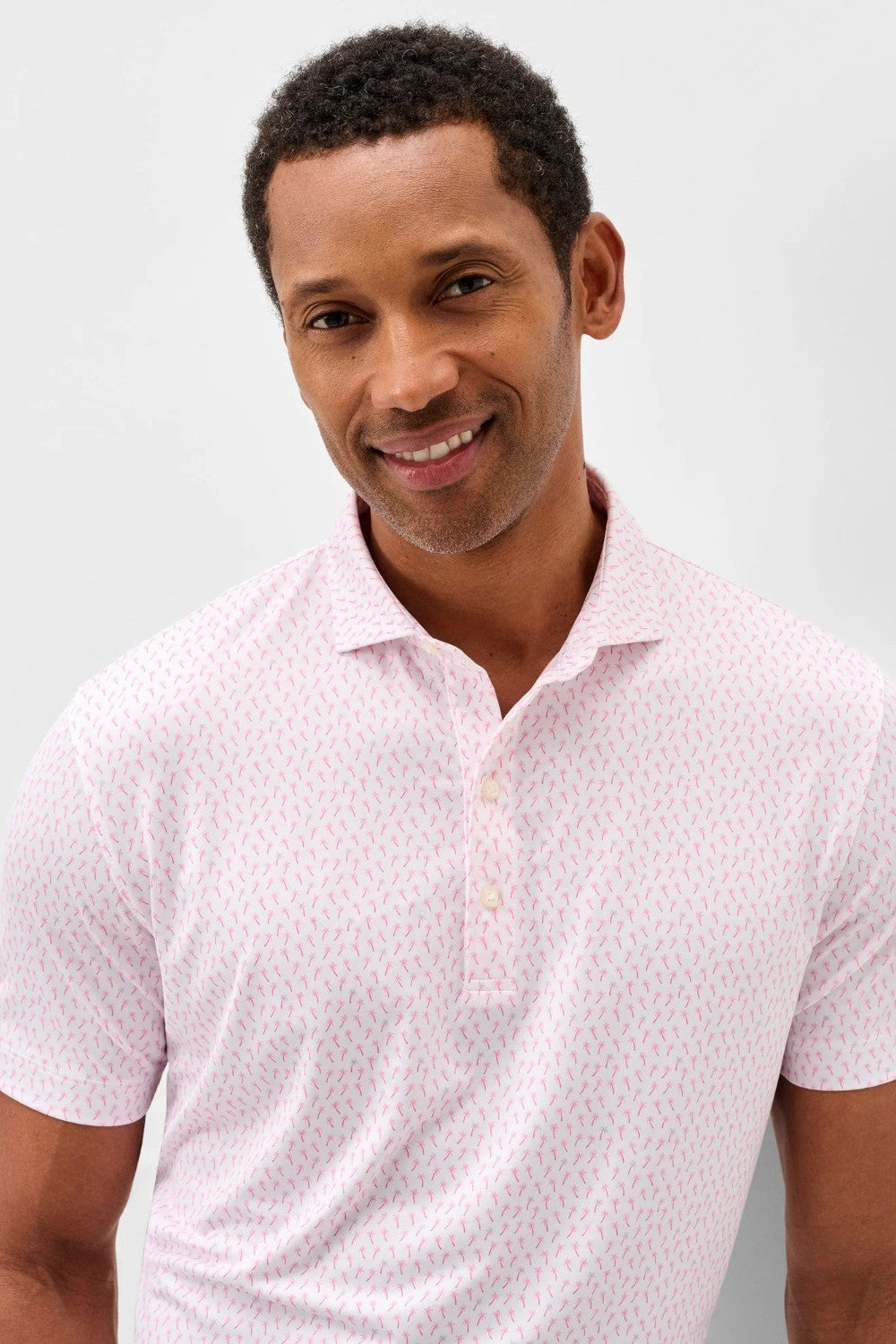Man wearing a white polo shirt with a subtle pattern against a light gray background