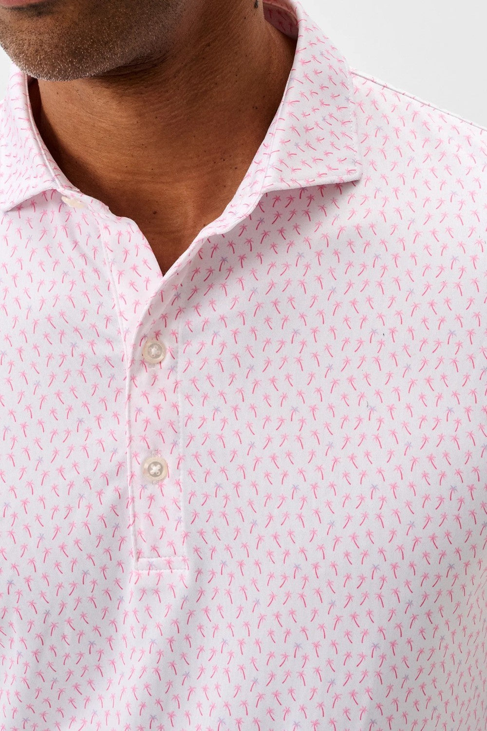 Close-up of a man wearing a pink patterned shirt with a blurred background