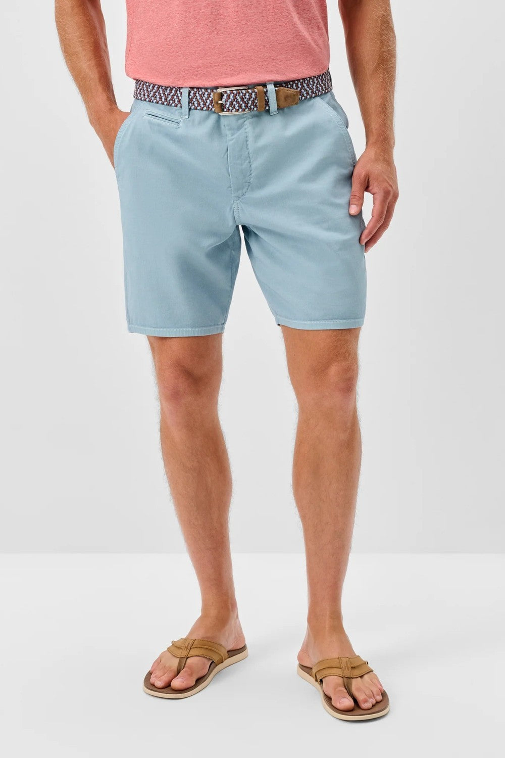 Person wearing light blue shorts and a pink shirt on a white background
