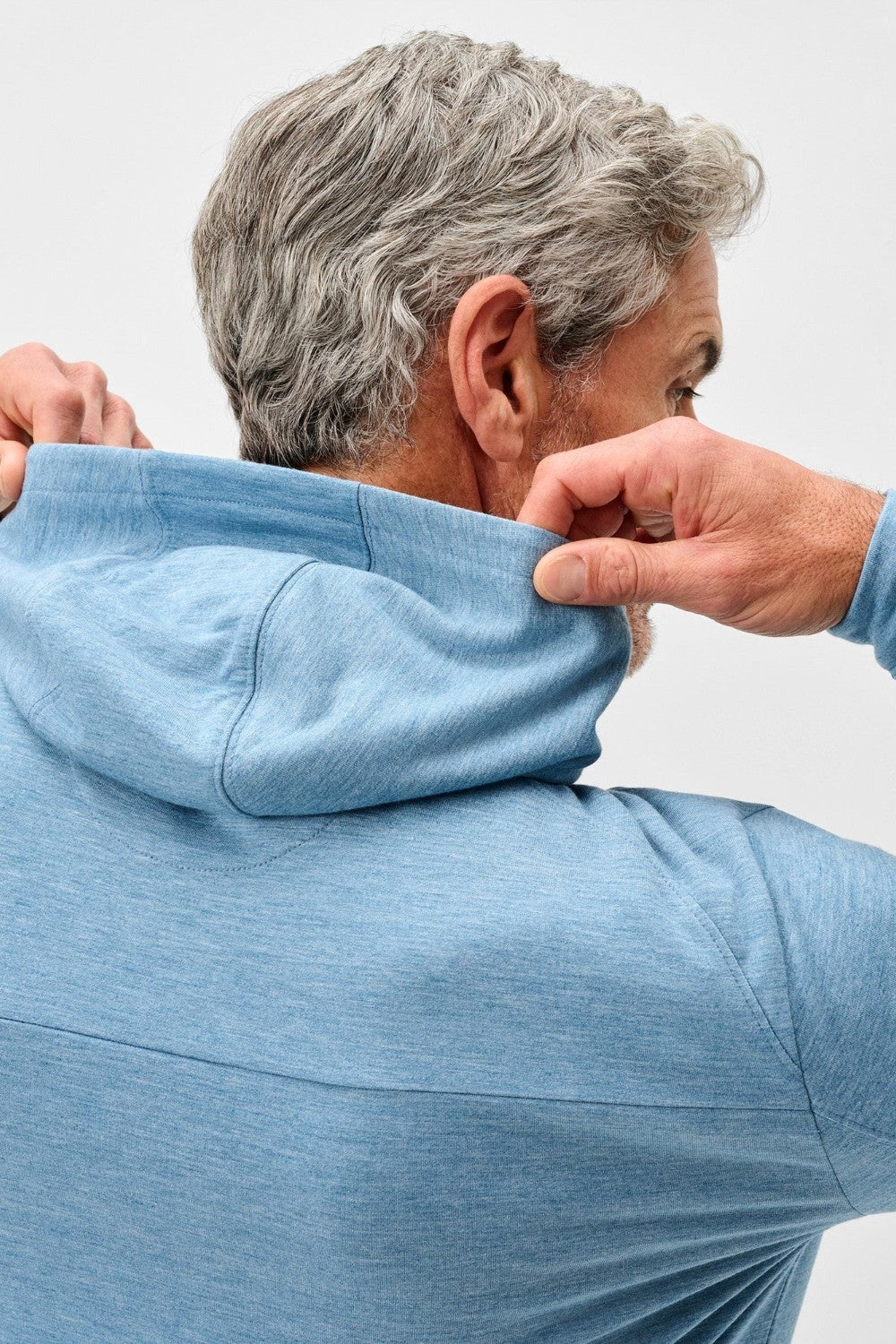 Person wearing a blue hoodie with a plain background
