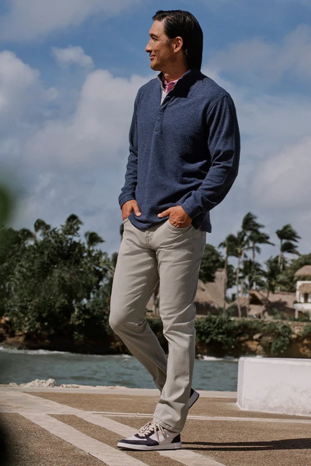 Man standing outdoors with a scenic background of trees and water.
