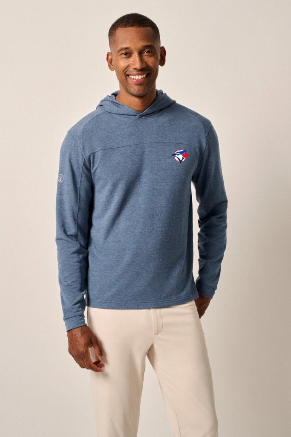 Man wearing a blue hoodie with a logo on a beige background