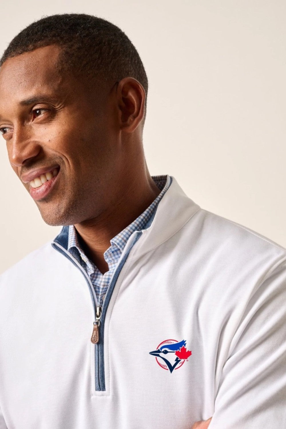 Man wearing a white jacket with a logo on a plain background