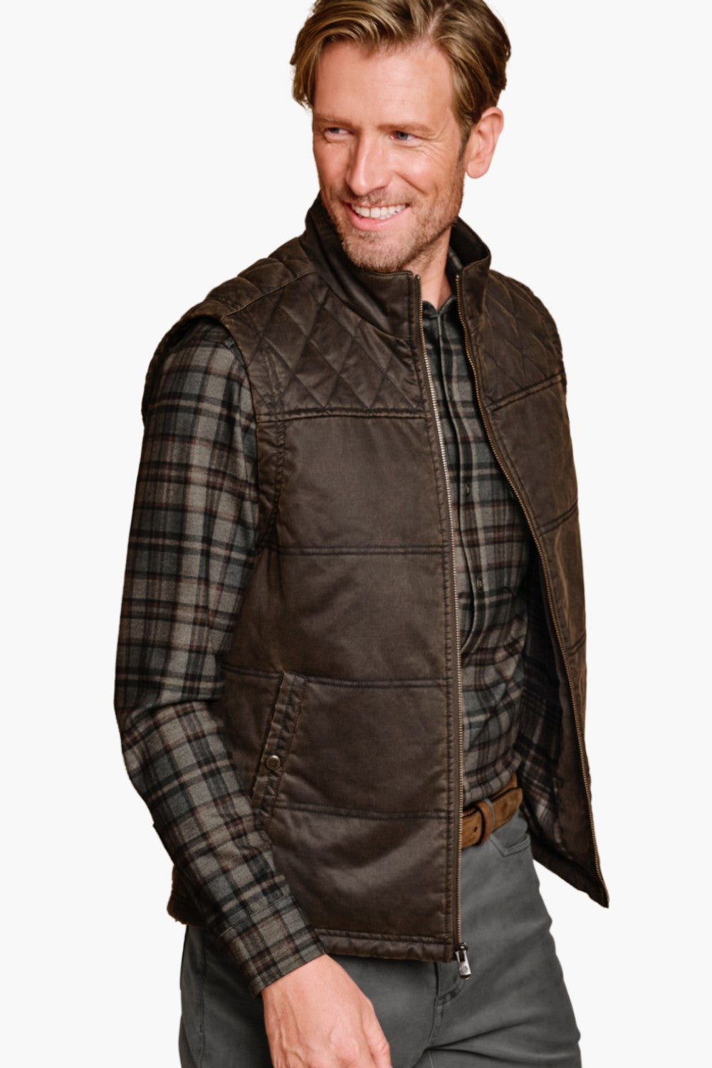 Man wearing a brown quilted vest over a plaid shirt on a white background