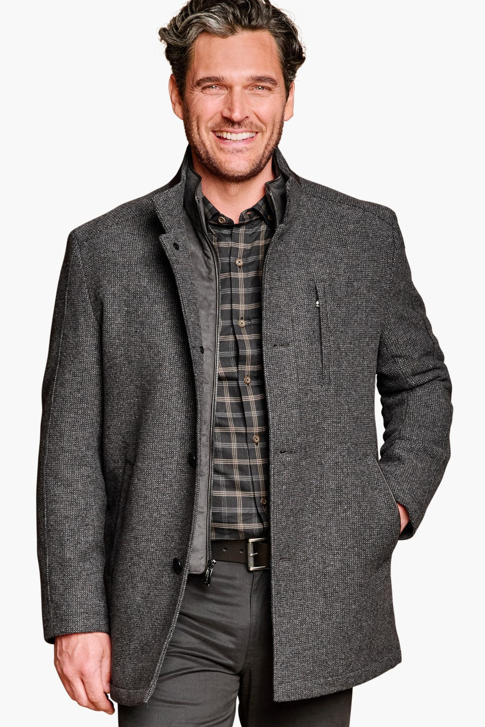 Man wearing a gray coat over a plaid shirt on a white background