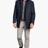 Man wearing a navy jacket, plaid shirt, and gray pants on a white background