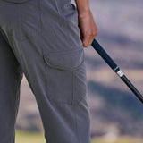 Person wearing gray pants holding a golf club with a blurred natural background