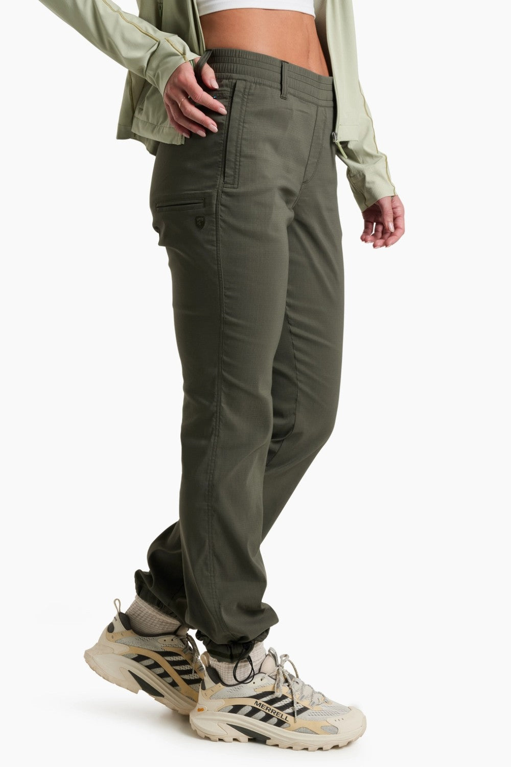 Person wearing olive green pants and a light green jacket on a white background