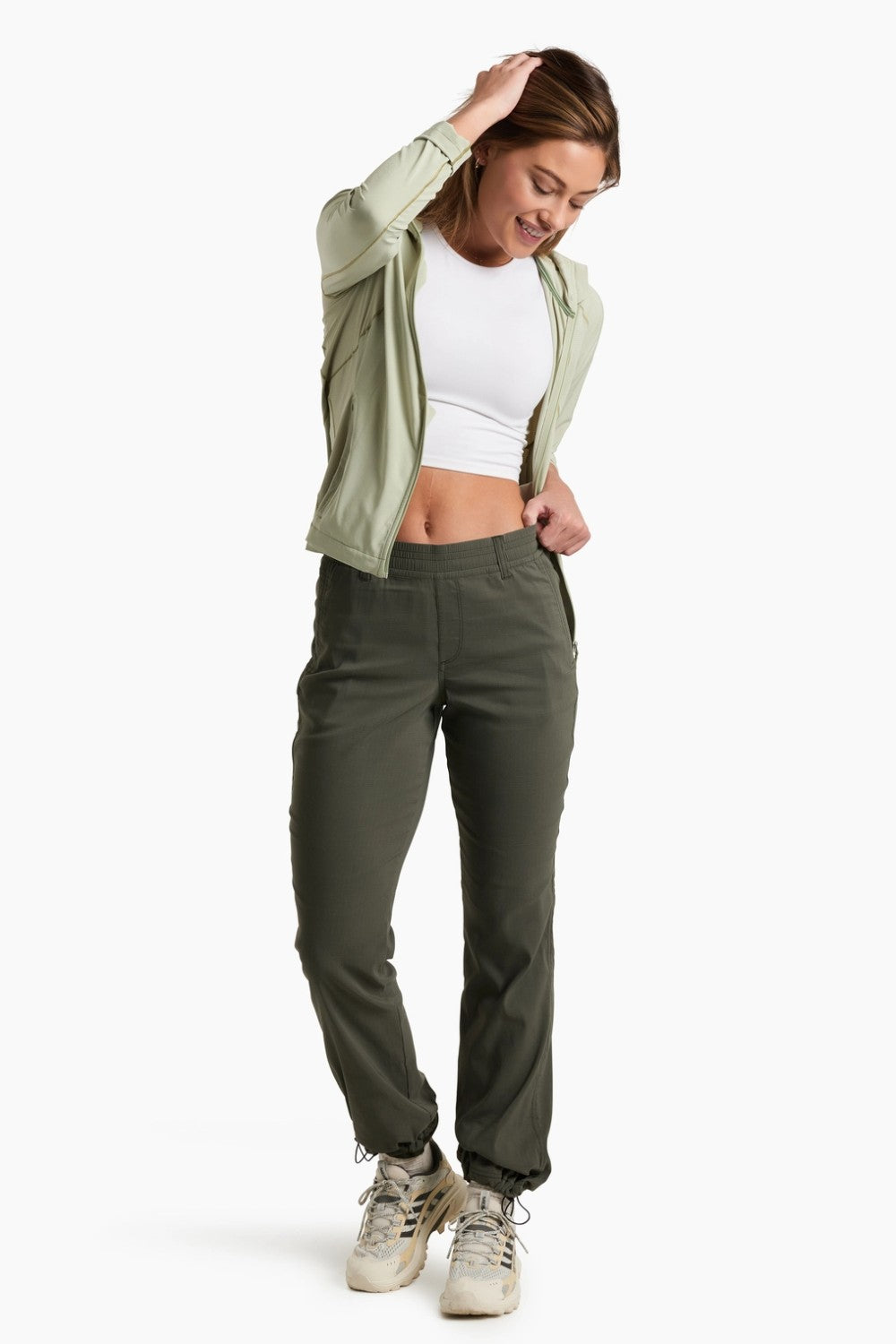 Woman wearing a green jacket, white top, and green pants on a white background