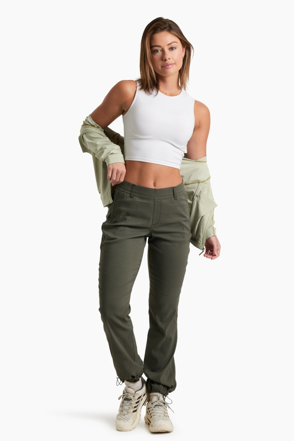 Woman wearing a white tank top and green cargo pants on a white background
