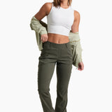 Woman wearing a white tank top and green cargo pants on a white background