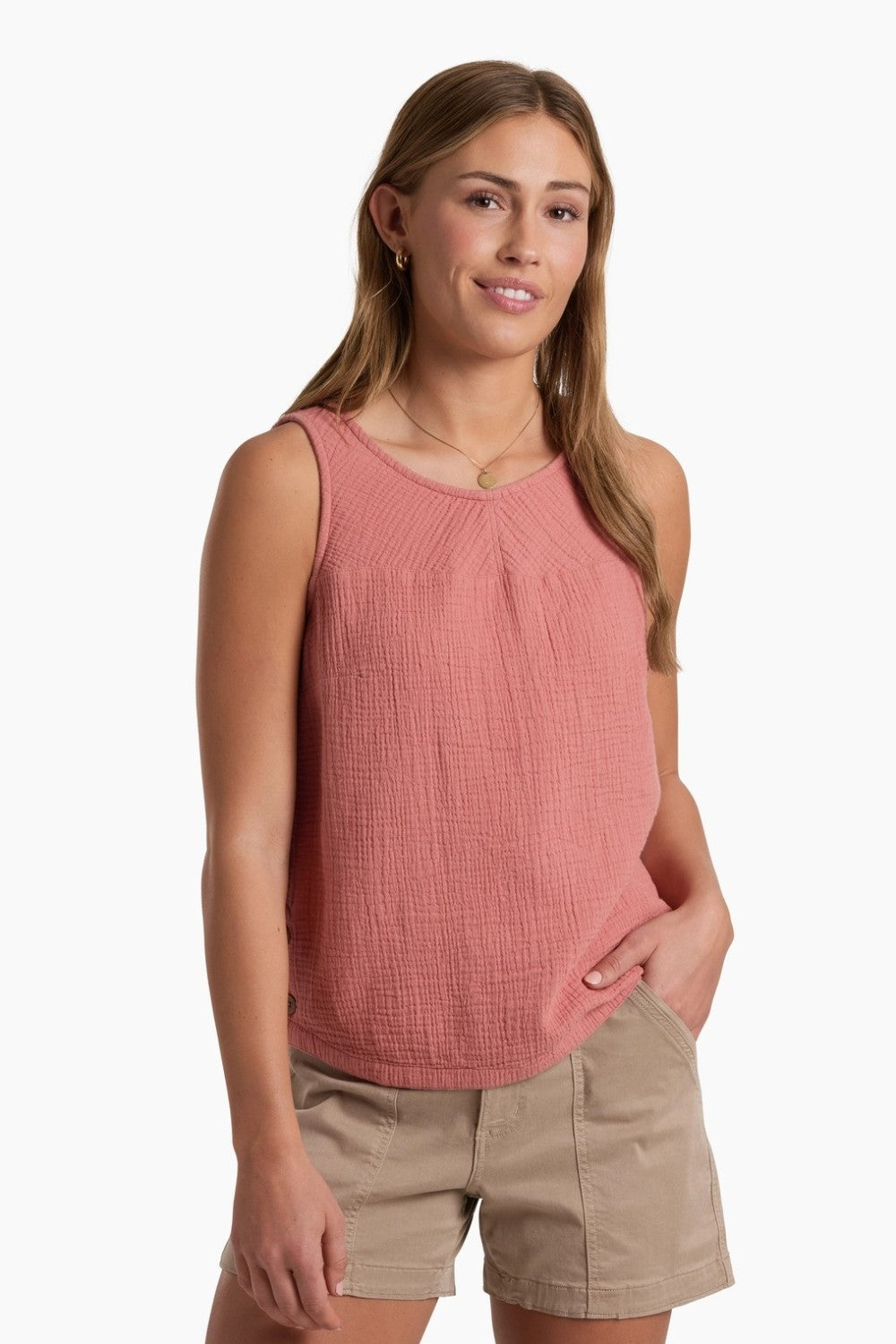 Person wearing a coral coloured tank top with beige shorts on a white background