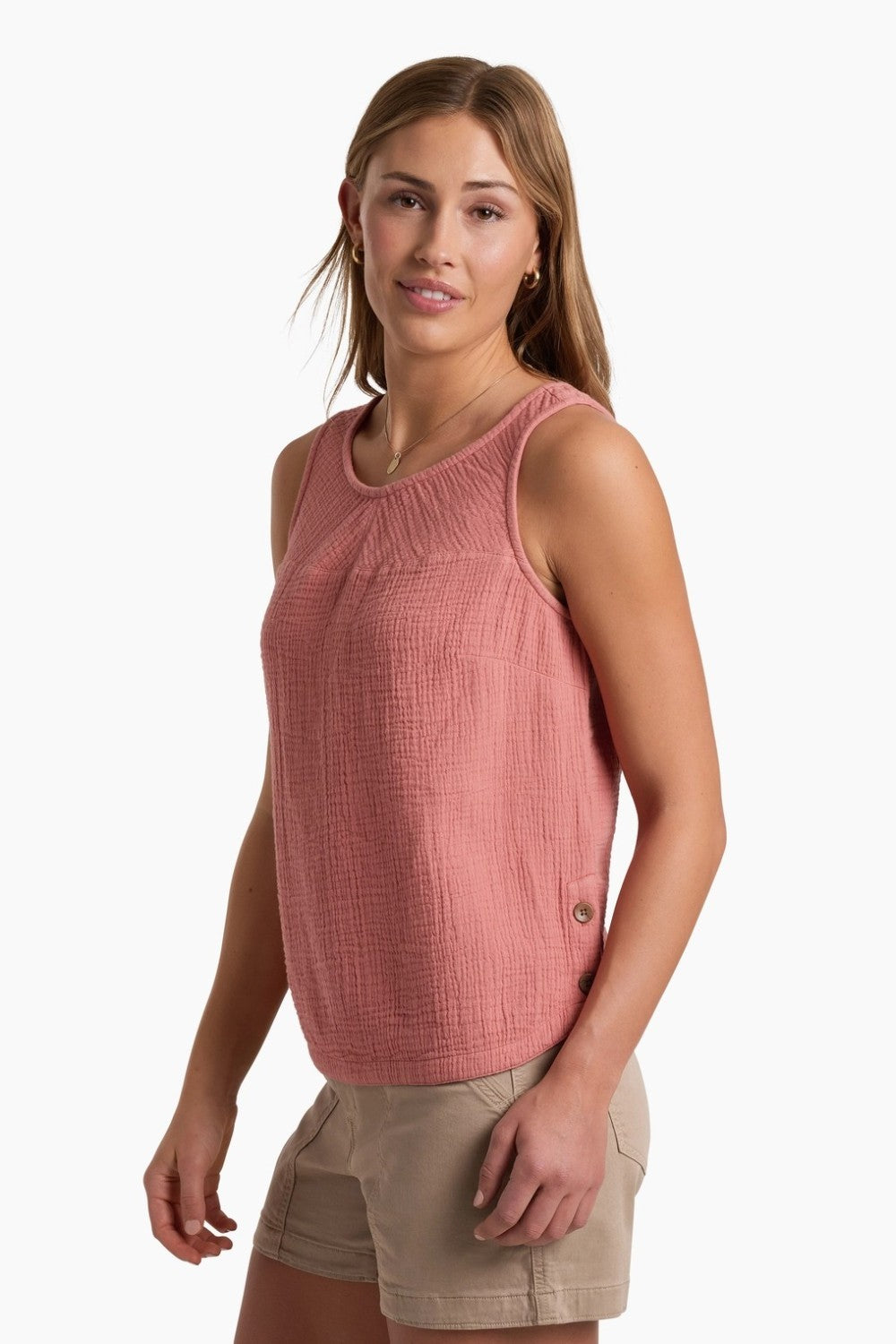 Person wearing a coral coloured tank top with beige shorts on a white background