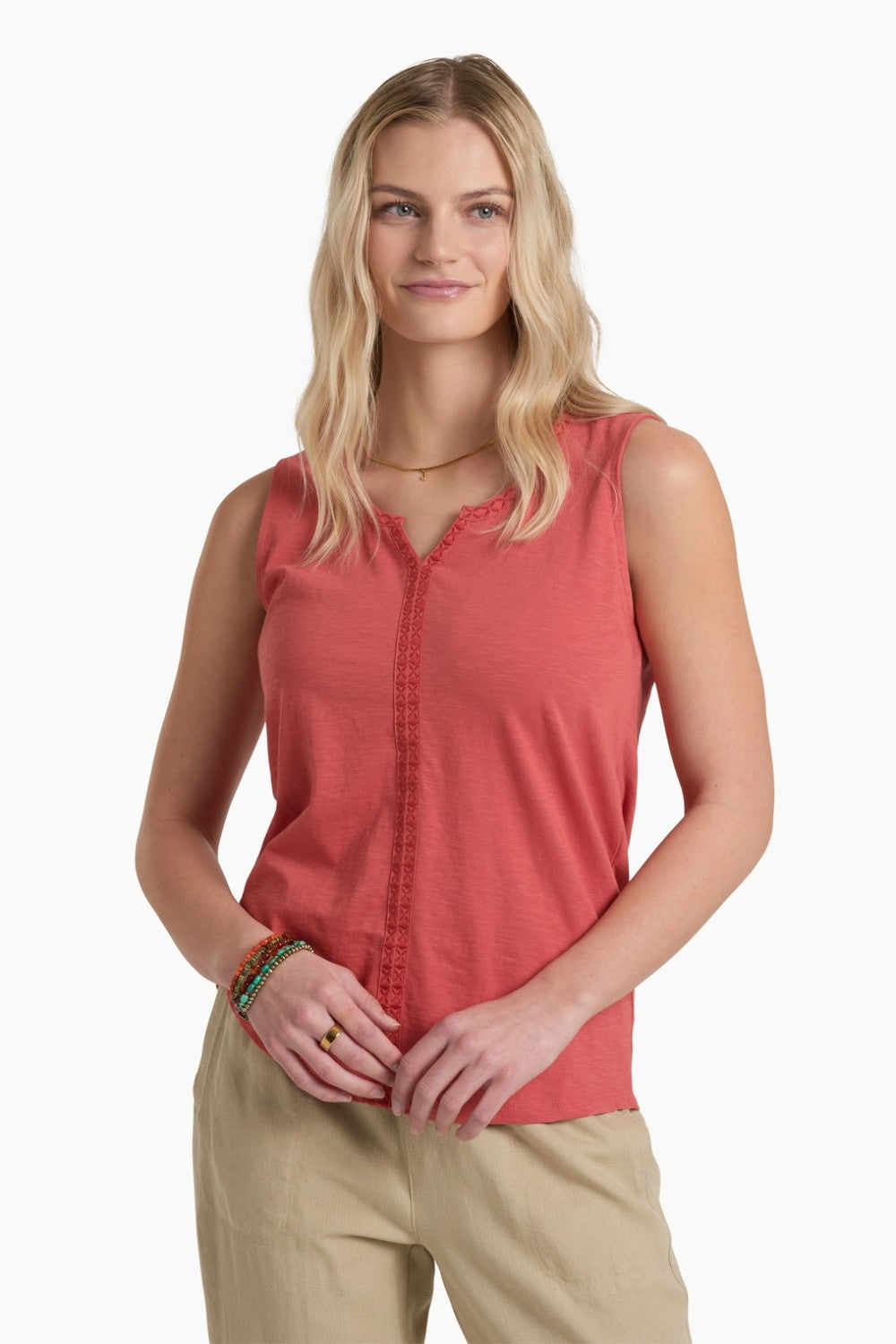 Woman wearing a red sleeveless top and beige pants on a white background