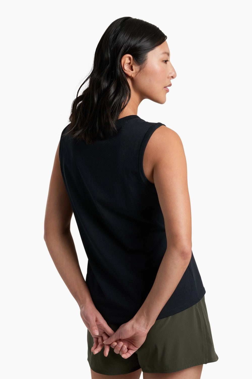 Woman wearing a black sleeveless top and green shorts on a white background