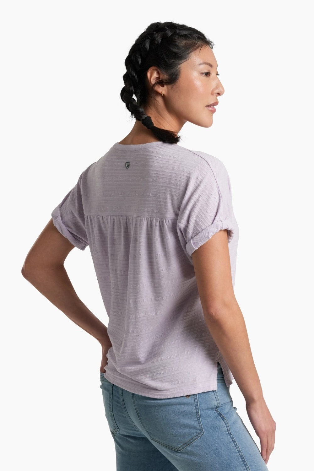Person wearing a soft purple top with blue jeans on a white background