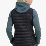 Woman wearing a black puffer vest over a teal and black sweater on a white background