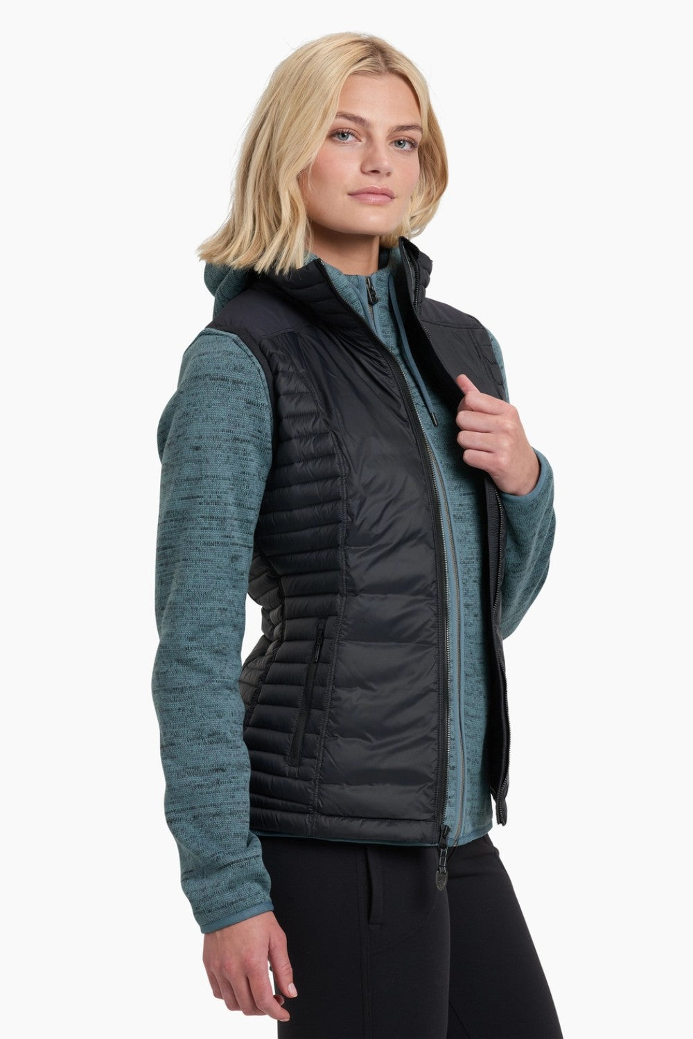 Woman wearing a black puffer vest over a teal shirt on a white background