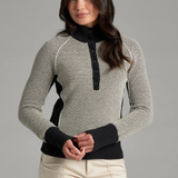 A woman wearing a textured gray and black knit sweater with a black collar and button placket, photographed against a light grey backdrop.