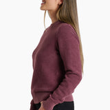 Woman wearing a maroon ribbed sweater on a white background