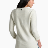 A woman wearing a ribbed knit long-sleeve sweater in a light cream color, paired with blue jeans, shown from the back, against a plain white background.