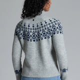 Woman wearing a gray sweater with blue patterned yoke against a gray background