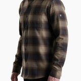 Man wearing a plaid shirt with a visible brand logo on a white background