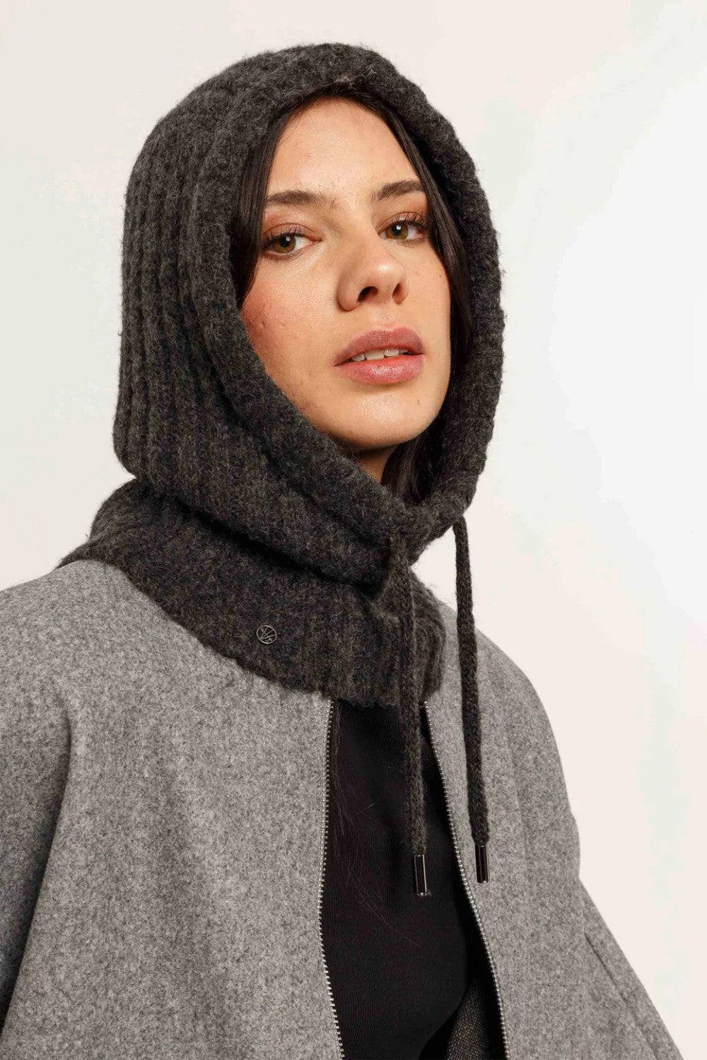Women wearing charcoal hooded scarf with grey jacket, black T  on light background